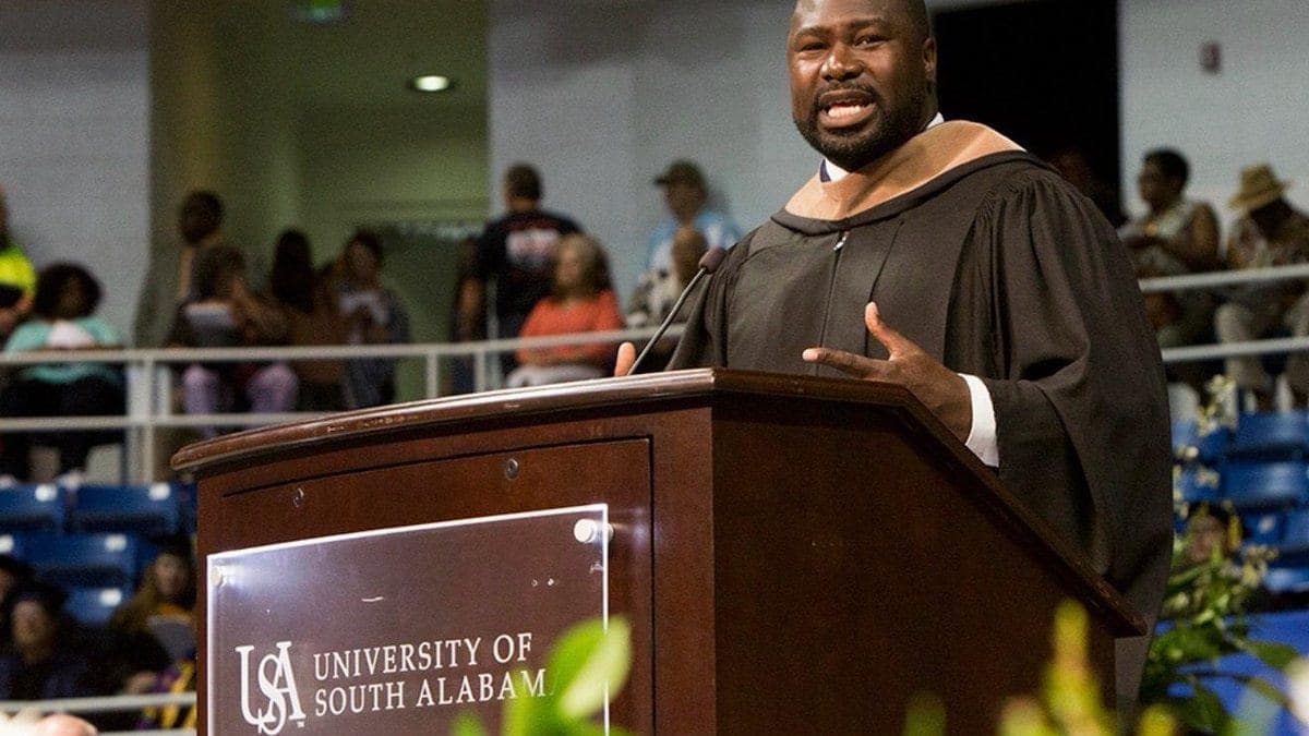 Ovie Mughelli delivering a university commencement keynote in academic regalia