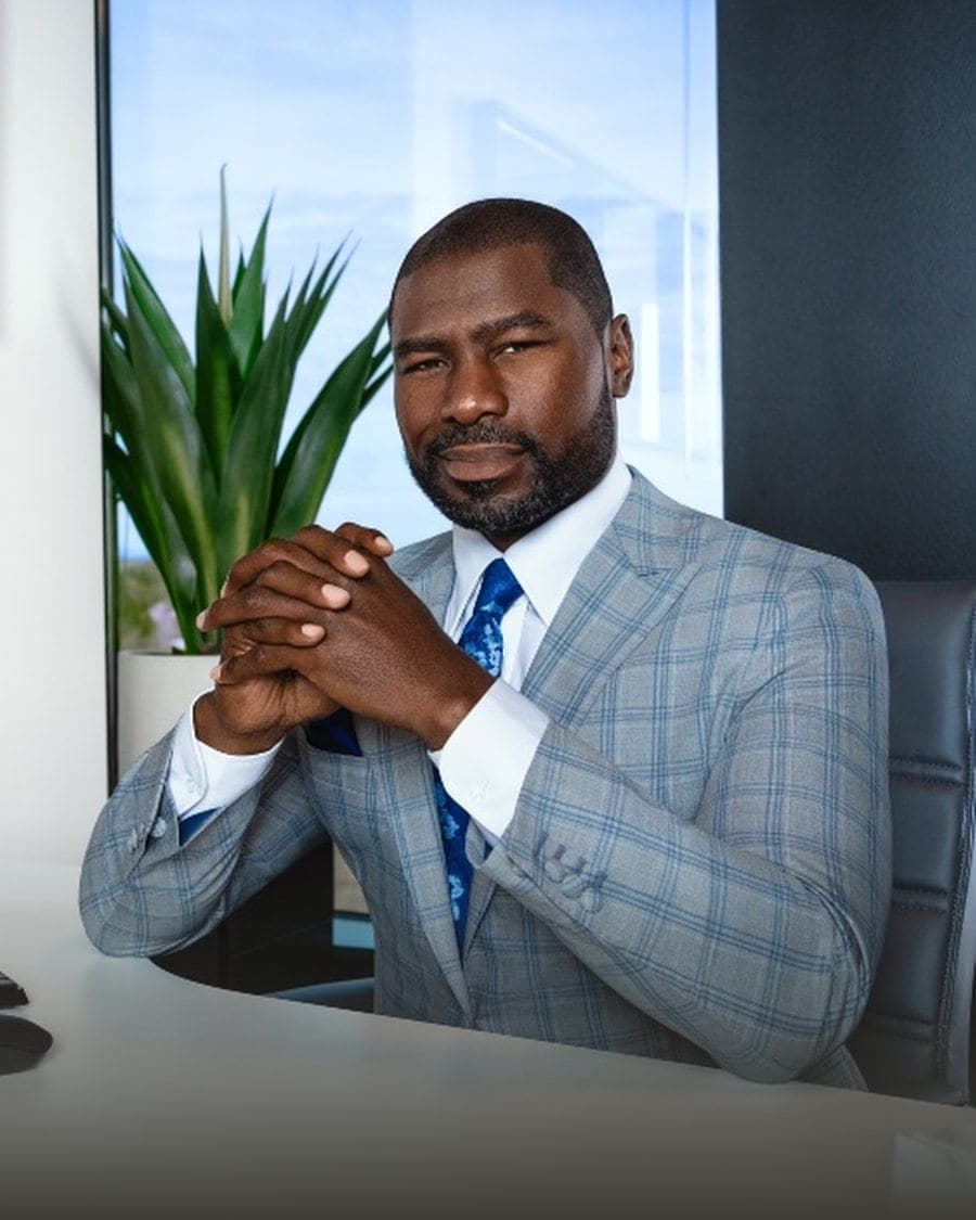 Ovie Mughelli in a tailored grey plaid suit