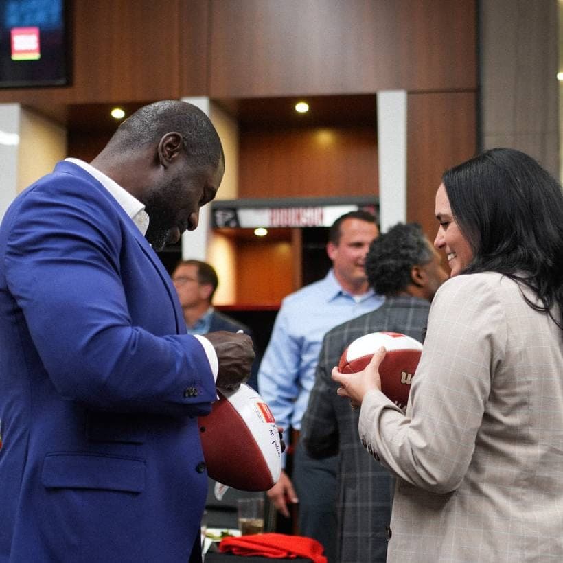 Ovie Mughelli signing footballs with guests at a corporate brand event