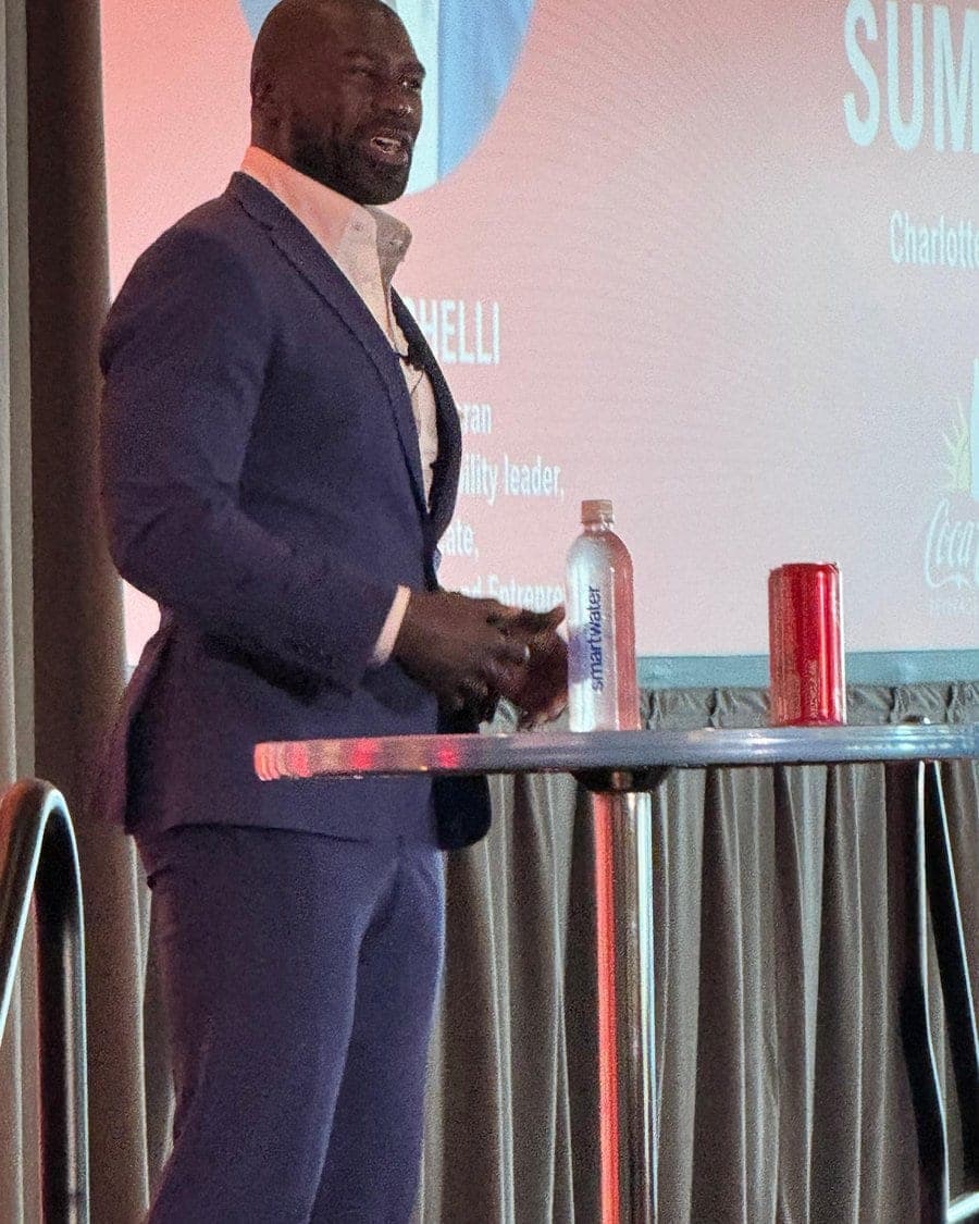 Ovie Mughelli speaking on stage with handheld microphone